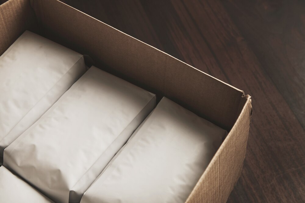 Closeup opened big carton box full of blank hermetic white packages with coffee or tea